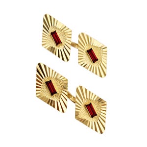 May include: A pair of gold cufflinks with a red gemstone in the center of each. The cufflinks have a diamond shape and a textured surface.