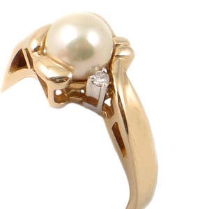 May include: A gold ring with a large white pearl and a small diamond. The ring is set in a delicate, swirling design.