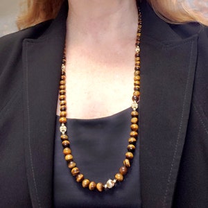 May include: A long gold necklace with tiger's eye beads and gold accents.