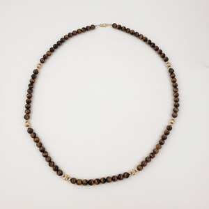 May include: A gold necklace with brown tiger's eye beads.