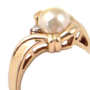 May include: A gold ring with a pearl and a diamond. The ring is designed with a knot-like band.