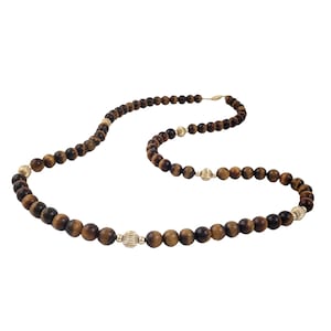May include: A long brown and gold beaded necklace with gold accents. The necklace is made of tiger's eye beads and gold beads.