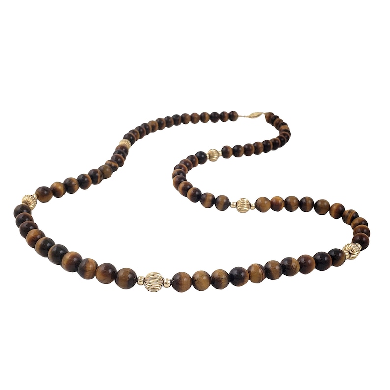 May include: A long brown and gold beaded necklace with gold accents. The necklace is made of tiger's eye beads and gold beads.