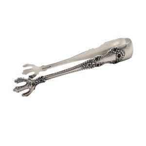 May include: Silver sugar tongs with an ornate floral design and a claw-like end. The tongs are marked "sterling".