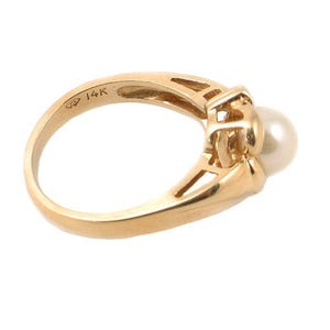 May include: A gold ring with a pearl and a 14K marking. The ring has a delicate design with a small pearl set in a gold setting.
