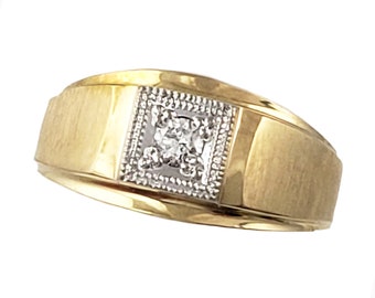 May include: A gold band ring with a square-shaped diamond set in a white metal frame.