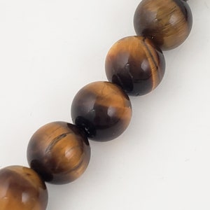 May include: A strand of tiger's eye beads. The beads are round and have a golden brown color with a subtle shimmer.