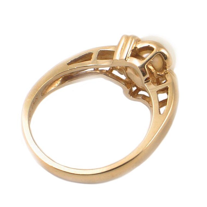 May include: A gold ring with a delicate design featuring a single pearl in the center.