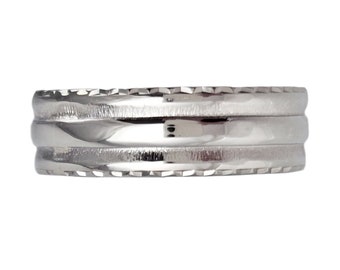 May include: A silver ring with a textured, ridged design. The ring has three bands, with the top and bottom bands featuring a repeating pattern of small, angled cuts. The middle band is smooth and reflective.