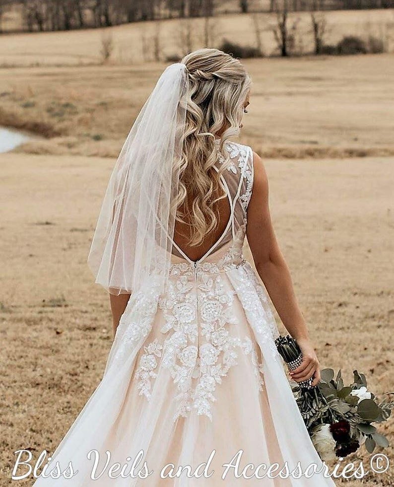 Short sheer wedding veil with one layer and raw edge, shown in fingertip length. Lightweight and modern, available in waist or fingertip