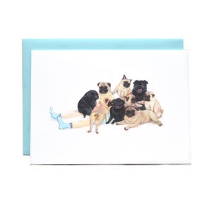 May include: A greetings card featuring a watercolour illustration of a group of fawn and black pugs gathered around a pair of legs wearing light blue socks with white polka dots, set against a plain white background with a light blue envelope.