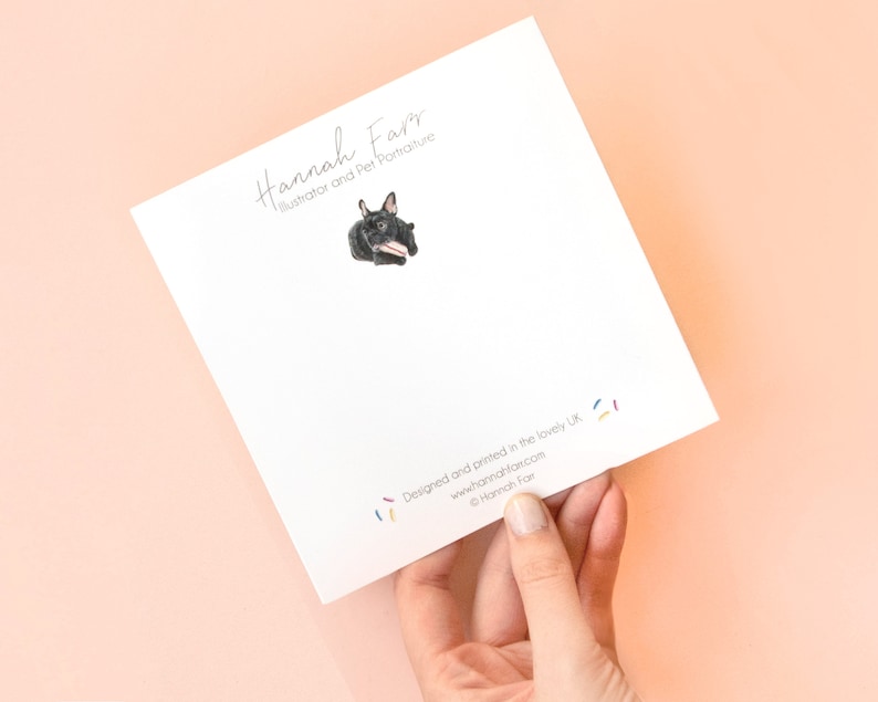 May include: A square white greeting card featuring a small illustration of a black French Bulldog holding a pink and white striped treat. The text reads Hannah Farr Illustrator and Pet Portraiture at the top and Designed and printed in the lovely UK at the bottom with the website and copyright information.