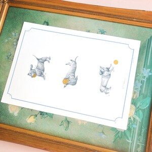 peachy pink background with gold vintage french inspired frames behind white dachshund print. three playing dachshund illustrated sketch. sausage dog with gold ball toy, gold foil print.