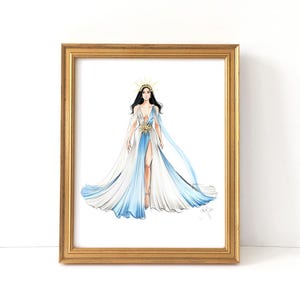 May include: A framed fashion illustration of a figure wearing a flowing white and light blue gown with a high leg slit, a gold sunburst waist accent, and a matching gold sunburst headpiece, presented in a metallic gold rectangular frame.