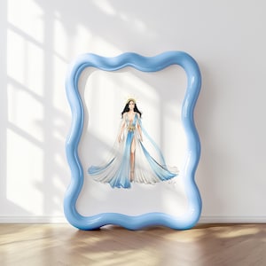 May include: A framed illustration of a figure wearing a flowing, floor-length gown with white and blue ombre panels, a deep V-neckline, and a gold starburst waist accent. The figure wears a gold crown. The frame is light blue with a wavy border.