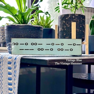 May include: A light blue wooden sign with a black skull pattern and the text "Vintage Blue The Vintage Hammer".