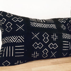 Peut inclure: Un coussin de décoration noir et blanc avec des motifs géométriques. Le coussin est fait d'un tissu doux et texturé.