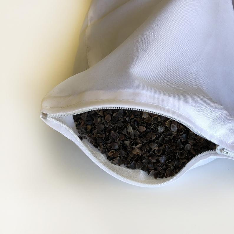 May include: A white pillowcase with a zipper open, revealing a filling of buckwheat hulls.