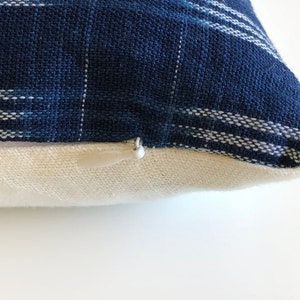 May include: A blue and white striped pillow cover with a zipper closure. The pillow cover is made of a soft, woven fabric.