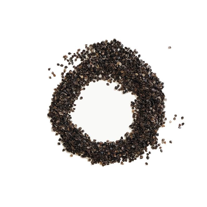 May include: A circle of dark brown buckwheat groats on a white background.