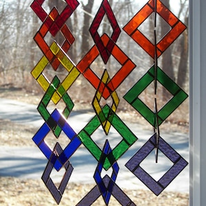 May include: A stained glass mobile with interlocking diamond shapes in red, orange, yellow, green, blue, and purple.