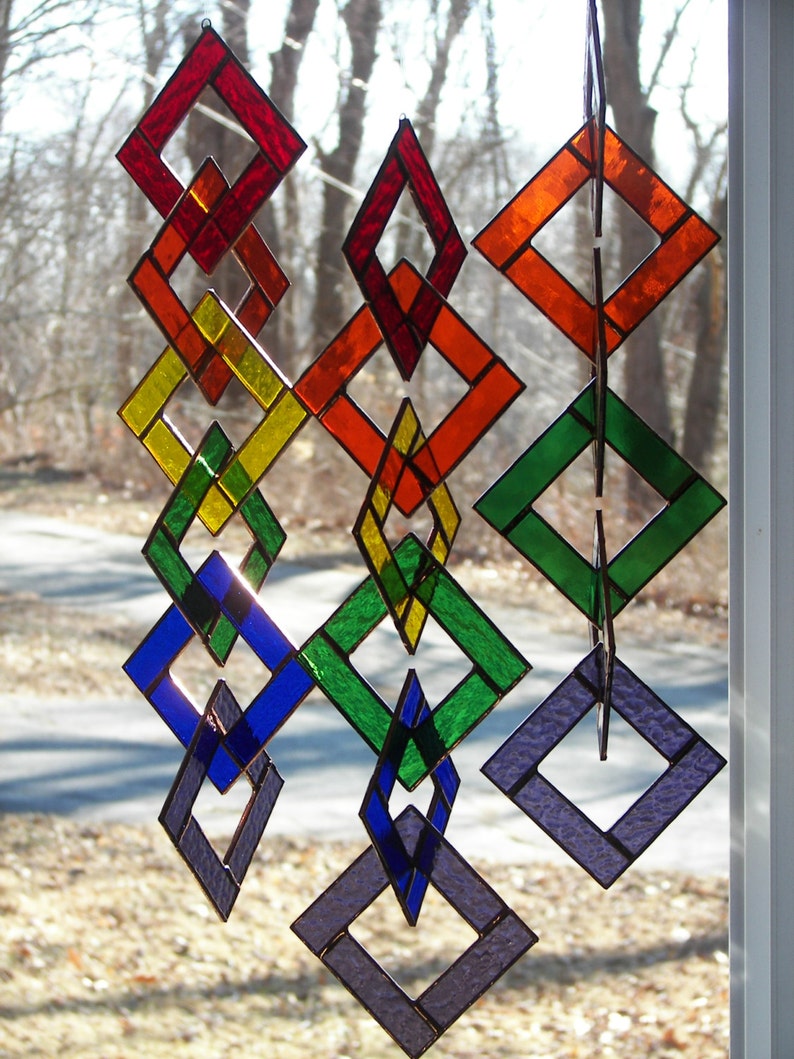 May include: A stained glass mobile with interlocking diamond shapes in red, orange, yellow, green, blue, and purple.