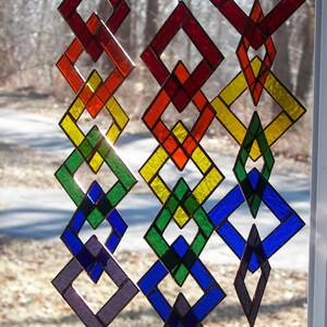 May include: A stained glass mobile with a rainbow of colors. The mobile is made up of interlocking diamond shapes. The colors are red, orange, yellow, green, blue, and purple.