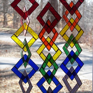 May include: A rainbow-colored stained glass mobile with diamond-shaped pieces. The mobile is made of red, orange, yellow, green, blue, and purple glass.