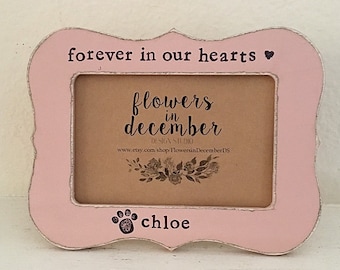 Pode incluir: Uma moldura rosa ornamentada com as palavras "forever in our hearts" e um símbolo de coração no topo. A moldura tem o texto "flowers in december" e o nome "chloe" com uma pegada.