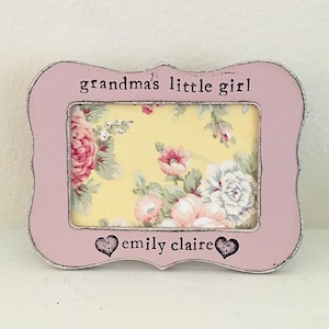 May include: A pink wooden picture frame with a floral pattern inside. The frame has the text "grandma's little girl" and "emily claire" on it.