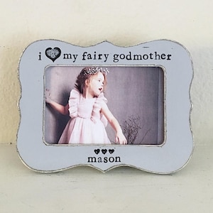 May include: A gray picture frame with the text "i love my fairy godmother" and a photo of a young girl in a white dress. The frame also has the text "mason" at the bottom.