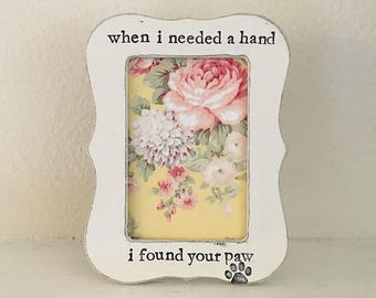 Pode incluir: Moldura de madeira branca com um padrão floral no interior e o texto "when i needed a hand i found your paw" com uma pegada de pata abaixo do texto.