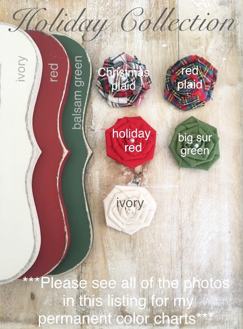 Puede incluir: Una colecci&oacute;n de flores de tela en varios colores, incluyendo marfil, rojo, verde y a cuadros. Las flores est&aacute;n dispuestas sobre una superficie de madera con un letrero que dice "Holiday Collection".