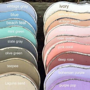 May include: A collection of 17 paint color swatches, each with a different color and name. The colors range from light to dark and include shades of blue, green, gray, pink, purple, and beige. The names of the colors are written in white text on each swatch.