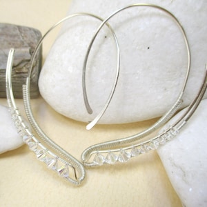 May include: A pair of silver hoop earrings with a delicate wire design and clear crystal accents.