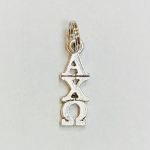 May include: Silver charm with the Greek letters AXQ, a popular sorority symbol.