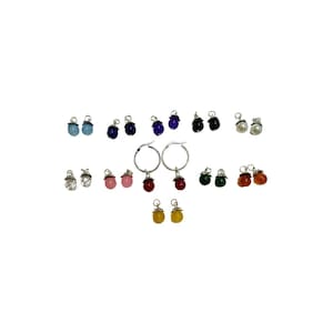 May include: Assortment of colorful gemstone earrings with silver hoops and drop charms. The earrings feature various colors, including blue, purple, pink, red, green, orange, and yellow.