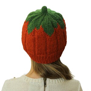 Puede incluir: Un gorro de punto con forma de calabaza, con cuerpo naranja y parte superior verde.