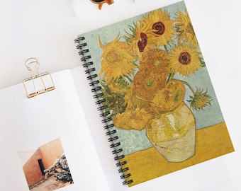 May include: A spiral bound notebook with a painting of sunflowers in a vase. The painting is by Vincent van Gogh and is in a yellow, orange, and brown color scheme. The notebook is on a white surface.