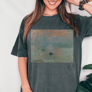 Pu&ograve; includere: Una maglietta oversize grigio antracite con una stampa del dipinto Impression, soleil levant di Claude Monet.