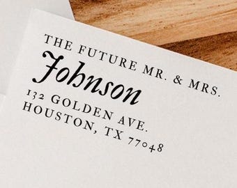 May include: White stationery with the text "THE FUTURE MR. & MRS. Johnson" printed in black. The address "132 GOLDEN AVE. HOUSTON, TX 77048" is also printed in black. The stationery is on a wooden surface.