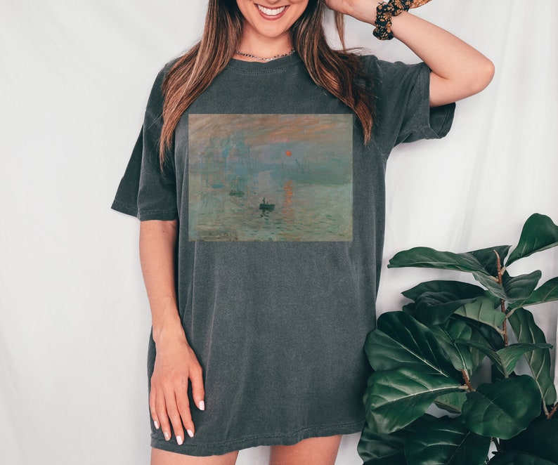 Pu&ograve; includere: Una maglietta oversize grigio antracite con una stampa del dipinto Impression, soleil levant di Claude Monet.