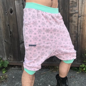 May include: Pink and gray patterned shorts with a mint green waistband. The shorts have a small pocket on the left side with a black label that reads "NOVA GEOMETRIA".