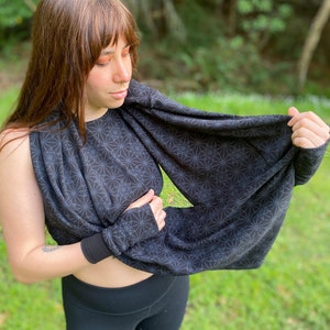 Könnte beinhalten: Ein schwarzer und weißer geometrischer Muster-Infinity-Schal mit einem schwarzen und weißen geometrischen Muster. Der Schal wird von einer Person mit langen braunen Haaren getragen.