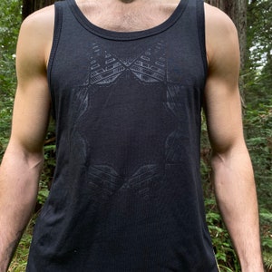 May include: Black tank top with a geometric design. The sleeveless shirt features a crew neck and a dark gray pattern across the chest. The tank top is made of a soft, dark fabric.