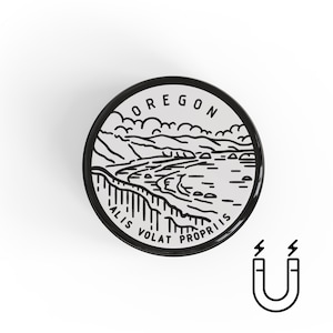 May include: A round magnet with a black border featuring a black and white illustration of an Oregon landscape. The word "OREGON" is at the top, and "ALIS VOLAT PROPRIIS" is at the bottom. A black and white magnet icon is in the lower right corner.