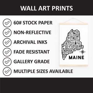 May include: A black and white wall art print of the state of Maine, with the state's outline and city names. The print is displayed on a wooden hanger. Text on the print includes "WALL ART PRINTS", "60# STOCK PAPER", and "MULTIPLE SIZES AVAILABLE".