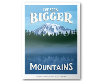 Puede incluir: Un póster de estilo vintage con un cielo azul y una cordillera reflejada en un lago. El texto dice "I've Seen Bigger Mountains" y "Mount Rainier National Park | Est. 1899".