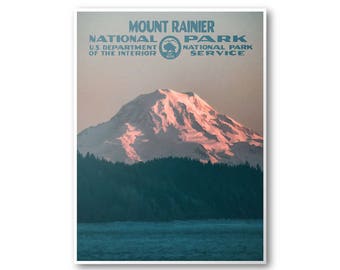 May include: A vintage travel poster for Mount Rainier National Park. The poster features a scenic view of the snow-capped mountain peak with a forest in the foreground and a body of water in the bottom of the image. The poster has the text "Mount Rainier National Park" at the top and "U.S. Department of the Interior National Park Service" at the bottom.