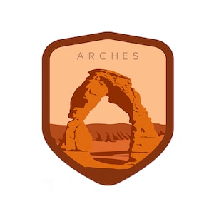 May include: A brown shield-shaped patch with the word "ARCHES" in white text at the top. The patch features a brown silhouette of Delicate Arch, a natural sandstone arch in Arches National Park, Utah.